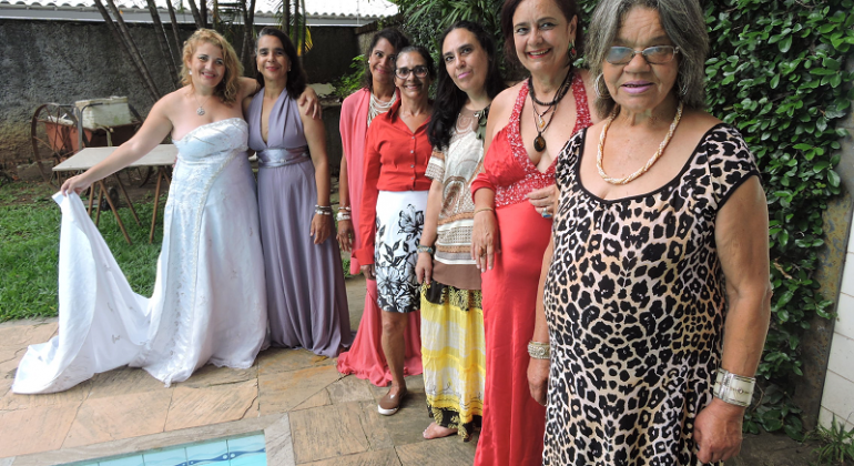 Prefeitura de Belo Horizonte Mulheres posam para foto usando vestidos longos, ao lado de uma piscina