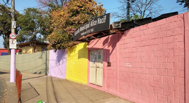 Muro da Escola Municipal Alice Nacif, pintada de lilás, amarelo e rosa. 