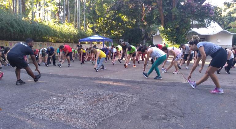 Mais de 20 corredores do Programa Movimenta BH fazem alongamento no Parque Municipal. 