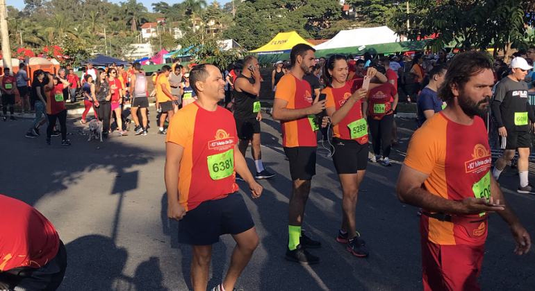 Pessoas com roupas de corrida e números em suas blusas caminham na concentração do evento de corrida