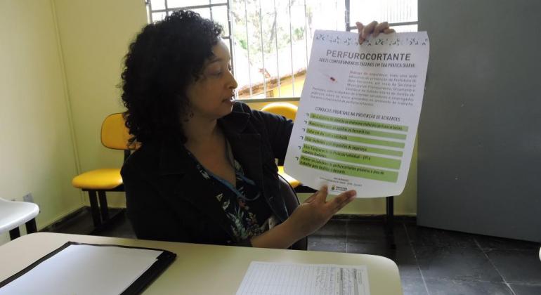 Treinamentos sobre segurança de trabalho nas unidades de saúde são realizados pela Secretaria Municipal de Planejamento, Orçamento e Gestão. Foto: Divulgação PBH Mulher mostra papel com instruções do curso de segurança do trabalho.