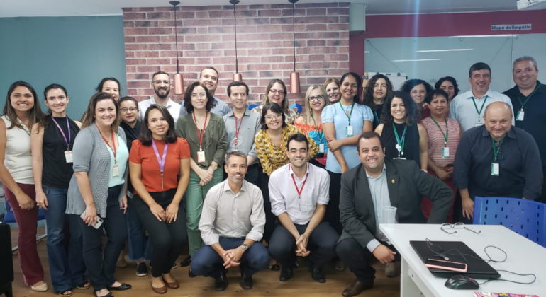 As oficinas “Experiência do Usuário do Serviço Público” e “Modelo de Custos de Serviços” visam melhorar o atendimento digital ao cidadão. Foto: Divulgação PBH Mais de vinte servidores posam para foto em uma sala.