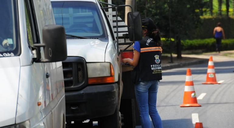 Técnica de fiscalização de BH aborda carro em Operação Oxigênico, durante o dia.