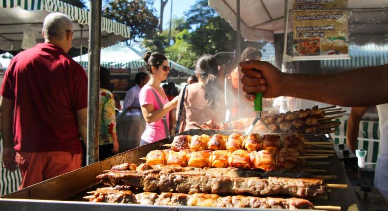 Churrasquinhos são oferecidos em uma barraca de uma feira da cidade