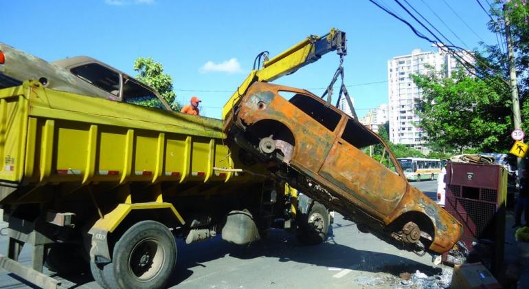 Abandonar carcaças de veículos nas ruas, além de gerar riscos à saúde da população, pode gerar multa no valor de R$ 1.444,91. Foto: Camila Viana/PBH Caminhão reboca carro abandonado durante o dia.