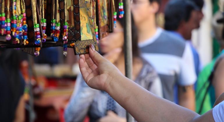 Cidadão confere artesanato em banca de feira ao ar livre. Foto ilustrativa. 