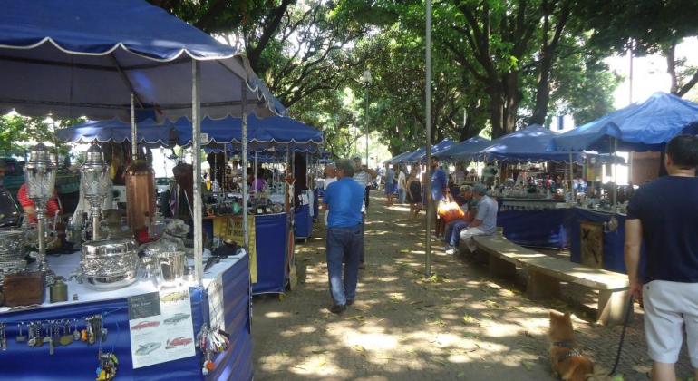 Homem caminha entre barracas de uma feira livre de rua