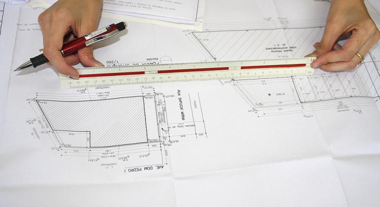 Pessoa usa régua para medições em planta de edificação