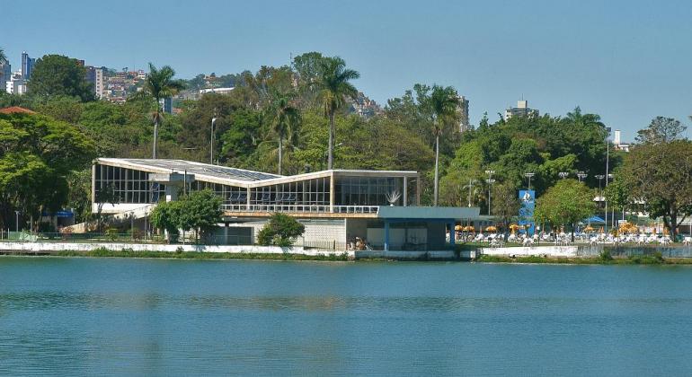 Fachada do Iate Tênis Clube, com Lagoa da Pampulha na frente, durante o dia. 