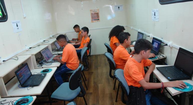 Foto da carreta do Conexão Aberta, com seis estudantes acessando computadores. Foto ilustrativa. 
