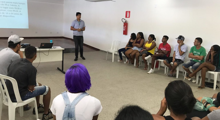 Foto: Divulgação PBH Instrutor da aula para onze alunos, sentados em cadeiras.