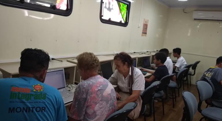 alunos do Telecentro acessando a internet gratuitamente e outros aprendendo a utilizar com a ajuda de um monitor.