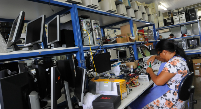 PBH amplia doação de computadores a pessoas em situação de vulnerabilidade Mulher mexendo numa bancada cheia de computadores.