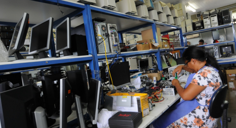 Mulher mexendo numa bancada cheia de computadores. 