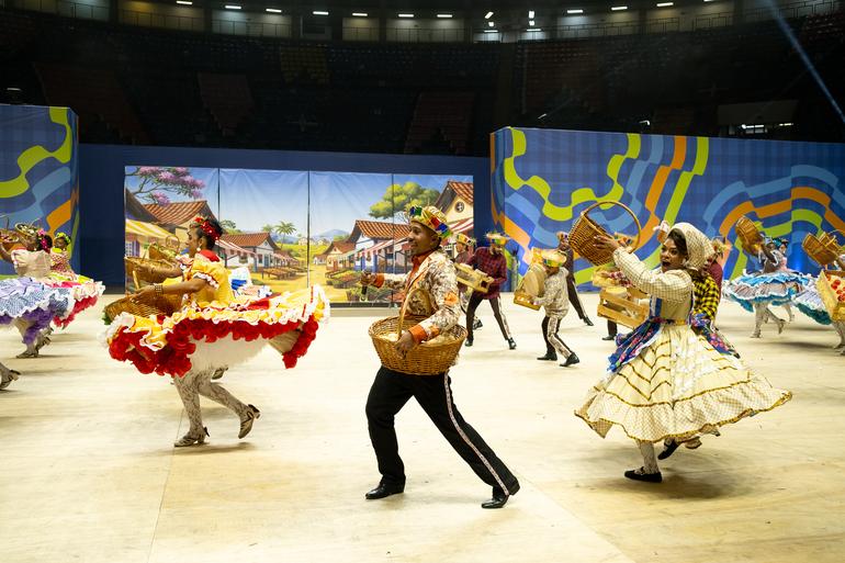 Apresentação de quadrilha em espaço próprio para o arraial de BH, bailarinos dançam vestidos com roupas características. 