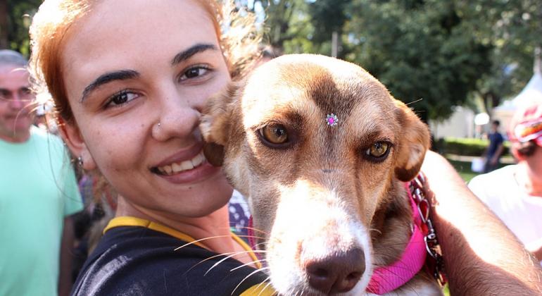Secretaria Municipal de Saúde realiza uma Feira de Adoção de Cães e Gatos, no sábado, dia 8/12. Foto: Márcio Martins/PBH Mulher segura cao no colo e sorri.