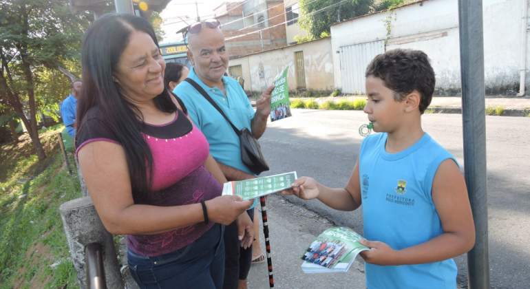 Grupo formado por estudantes de escola municipal e trabalhadores do centro de saúde participaram de caminhada educativa de combate à dengue. Foto: Divulgação PBH Aluno de escola municipal dá panfleto informativo a moradora de bairro, durante o dia.