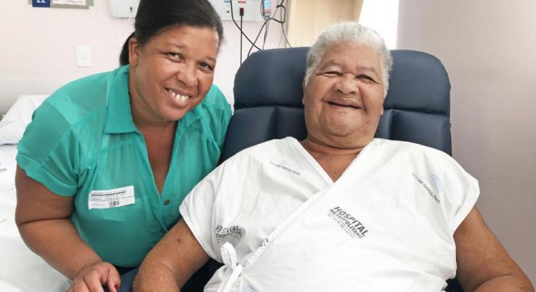 Uma profissional da saúde ao lado de paciente em sala de hospital