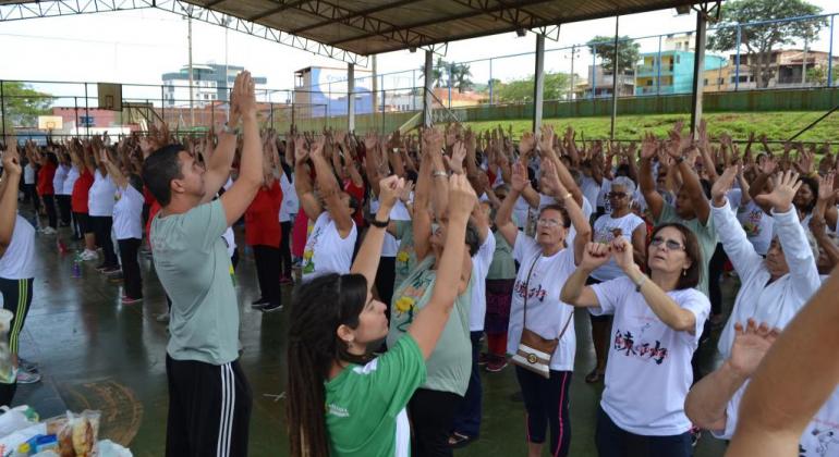 Belo Horizonte oferece terapia chinesa em praças e parques. Foto: Divulgação/PBH Dezenas de pessoas com as mãos pra cima praticando Lian Gong