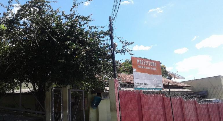 Fachada do Centro de Saúde Taquaril com tapumes devido a revitalização, durante o dia. 