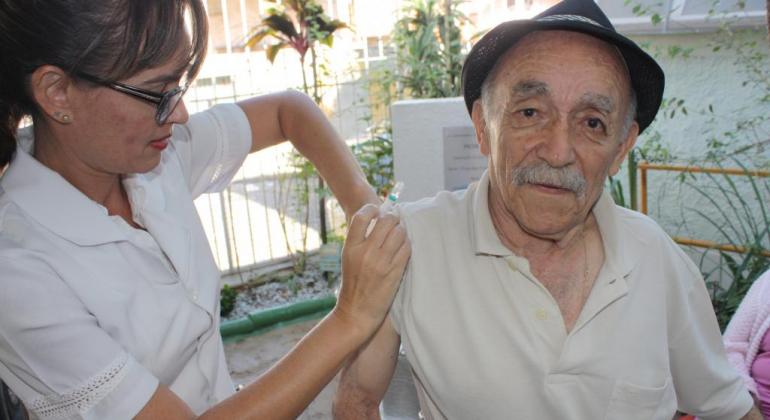 Foi iniciado o cadastramento de pessoas acamadas e residentes em casas de repouso para receber a vacina contra Influenza em domicílio. Foto: Divulgação PBH Idoso recebe vacina de técnico de saúde.
