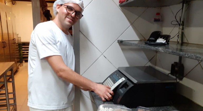 Duzentos cidadãos em sofrimento mental foram encaminhados para os empregos pelos nove centros de convivência da Prefeitura. Foto: Leila Porto Homem de blusa branca e touca, pesa alimentos.