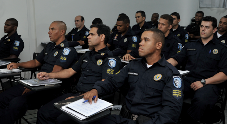 Mais de doze guardas municipais, sentados, assistindo a aulas de capacitação.