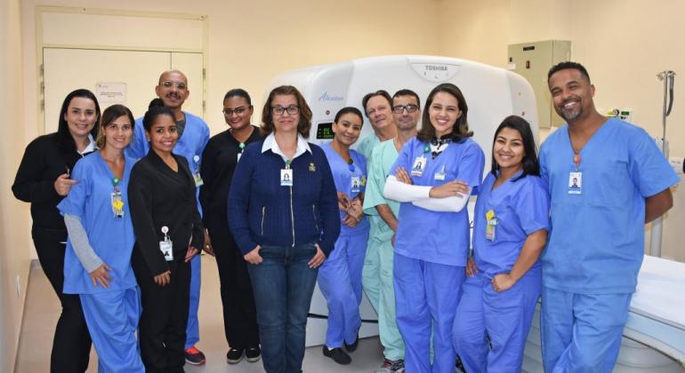 Mensalmente, são oferecidos cerca de 5.500 exames para pacientes externos oriundos de Centros de Sáude, UPAs e hospitais. Foto: Álvaro Miranda Equipe médica de 12 pessoas em frente ao duplex scan, equipamento que faz escaneamento do corpo e produz imagens.
