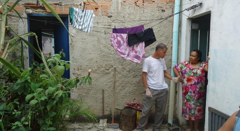 Profissional informa à moradora sobre os perigos da dengue na porta de sua casa