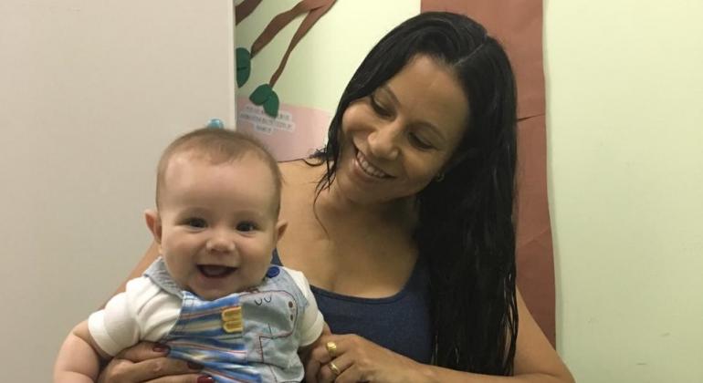 Fernanda, mãe do pequeno Tiago, separa alguns minutos para ordenhar o leite que vai para doação para o Centro de Saúde Pompeia todos os dias. Foto: Divulgação PBH Mãe segura bebê sorridente.
