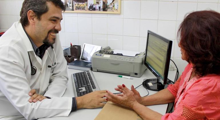 Prefeitura investe na contratação de profissionais da saúde Médico atende mulher em consultório