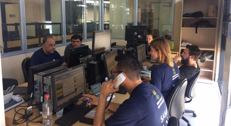 Presencialmente ou por meio do atendimento médico telefônico, SAMU de Belo Horizonte salva centenas de vidas todos os dias. Foto: Divulgação PBH Quatro atendentes do Samu em uma sala com telefones e computadores.