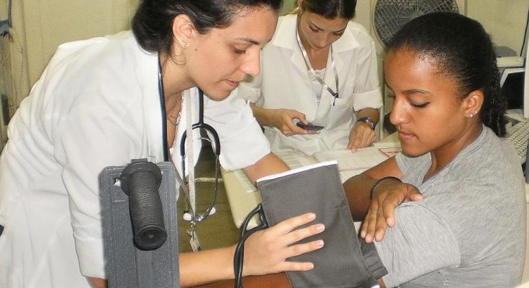 Duas pessoas atendem uma pessoa em posto de saúde