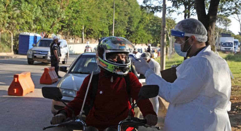 Prefeitura reativa barreiras sanitária em avenidas, rodoviária e metrô de BH Enfermeiro medindo a temperatura de motociclista