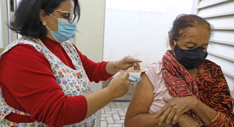 Vacina contra a Gripe continua disponível nos Centros de Saúde de Belo Horizonte Enfermeira aplicando vacina em uma senhora