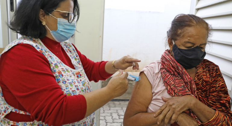 Enfermeira aplicando vacina em uma senhora