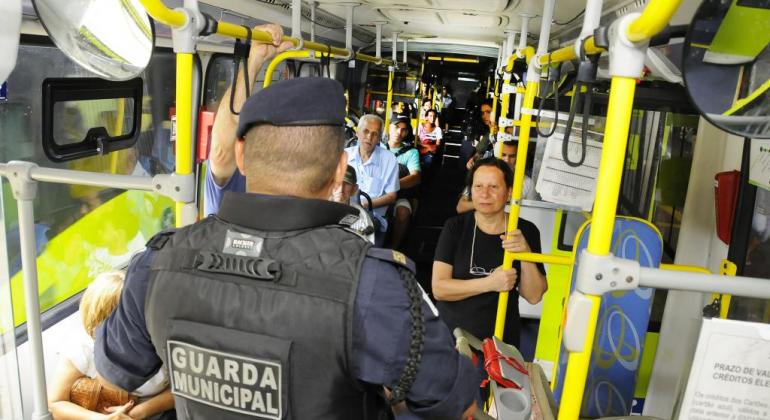 Agente da Guarda Municipal de costas, dentro de um ônibus