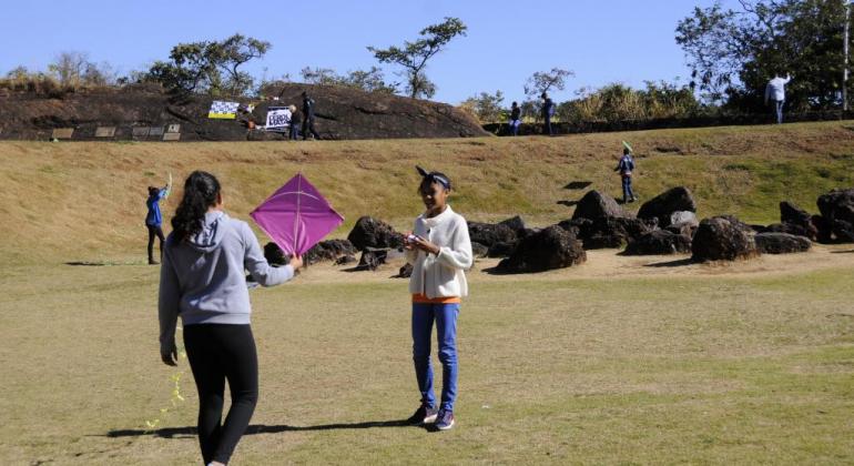 Cerca de 40 alunos de escolas municipais participaram do festival de pipas promovido pela Prefeitura no Parque das Mangabeiras no dia 12/7. Foto: Rodrigo Clemente/PBH Quatro jovens empinam pipa nos Parque das Mangabeiras, durante o dia.