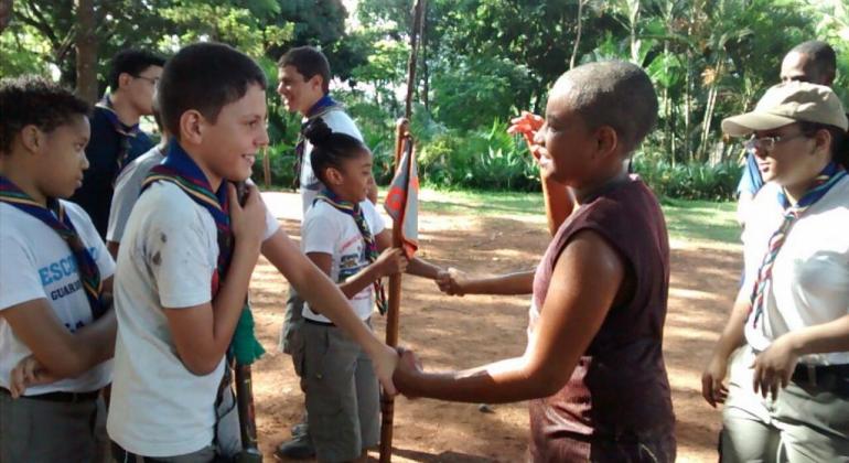 Escoteiros cumprimentam criança em uma praça