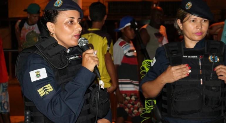 Duas guardas municipais em evento carnavalesco realizando ação de conscientização contra assédio
