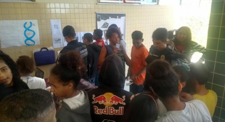 Na terça, dia 9/7, os agentes da Patrulha Escolar estarão em escola municipal para levar as orientações aos alunos do ensino fundamental. Foto: Divulgação PBH Dez adolescentes ao redor de Guarda Mumicipal, que dá explicações.