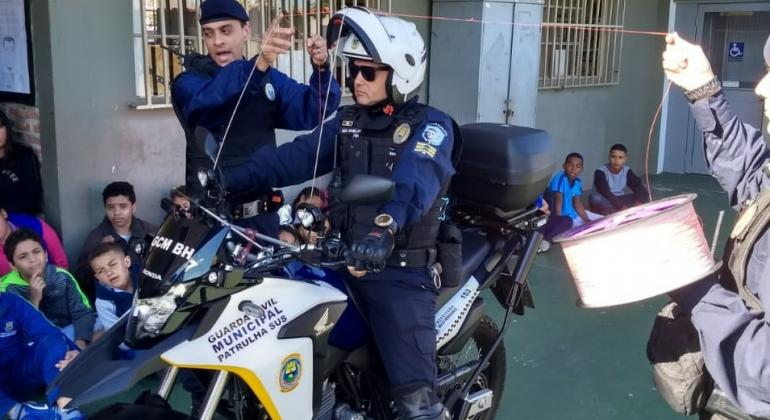 Guardas municipais mostram a alunos linha que poderia atravessar moto com duas antenas, explicando o perigo das pipas com cerol, durante o dia.