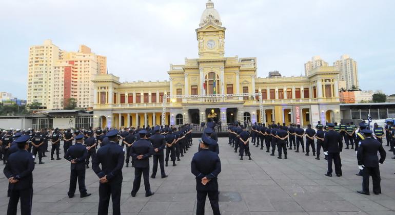 Mais de oitenta guardas municipais em formação em frente à Praça da Estação, ao cair da tarde. 