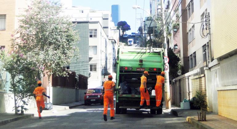 Confira os serviços de limpeza urbana no feriado de Corpus Christi Equipe da SLU fazendo a coleta do lixo com caminhão
