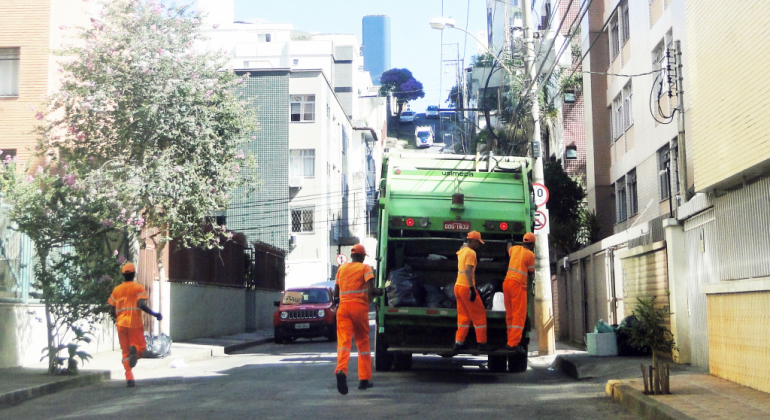 Equipe da SLU fazendo a coleta do lixo com caminhão