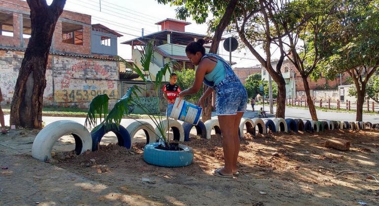 Recente levantamento da Superintendência de Limpeza Urbana apontou uma redução dos pontos de deposição clandestina de resíduos na capital. Foto: Divulgação PBH Cidadã rega planta rodeada por pneus em antigo ponto de deposição clandestina de resíduos.