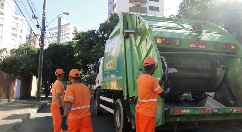 SLU recolheu mais de 680 mil toneladas desses rejeitos nas casas e no comércio, quase 25 mil toneladas a mais do que em 2017. Foto: Melissa Reis/PBH TRês garis ao lado de caminhão delixo em uma rua de Belo Horizonte, durante o dia.