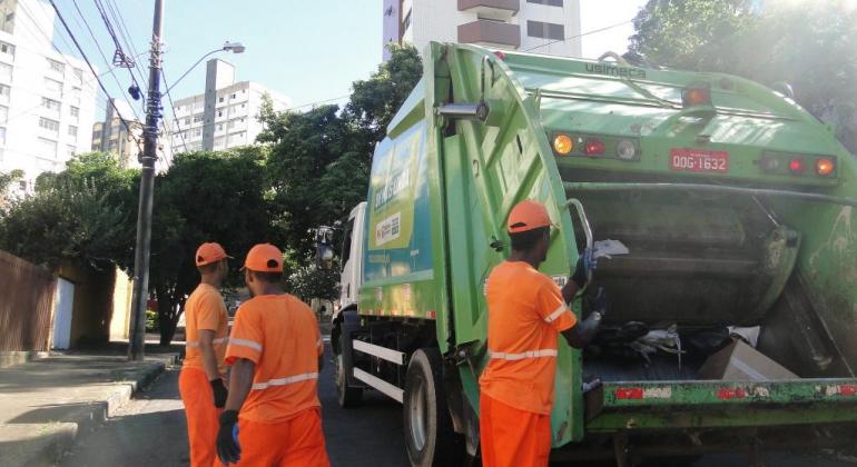 TRês garis ao lado de caminhão delixo em uma rua de Belo Horizonte, durante o dia. 