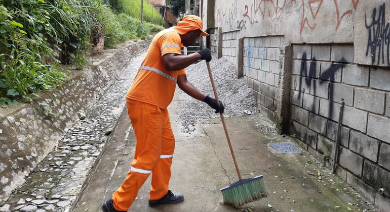 Aproximadamente 300 mil moradores de 65 Zeis são beneficiados com os serviços regulares de limpeza urbana, feitos por 234 garis. Foto: Divulgação PBH Gari vale rua, durante o dia.