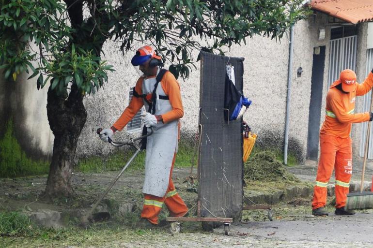Serviço de capina e roçada Dois garis realizam a capina e a roçada de uma via pública de Belo Horizonte